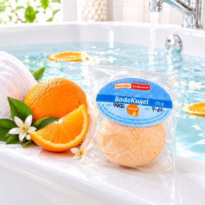Handgemachte Badekugel Orange mit Orange als Deko, liegend auf einem Badewannenrand
