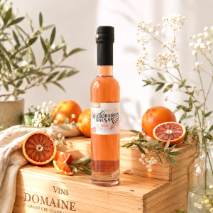 Im Focus: Durchsichtige Glasflasche 250ml mit Schraubverschluss, gefüllt mir hell orange Farben Blutorangenessig, stehend auf einer alten Weinkiste