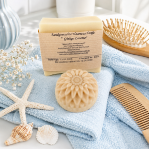1 handgemachte Haarseife Ginkgo Limette und 1 kleines Stück feste Spülung, liegend auf Handtücher im Badezimmer